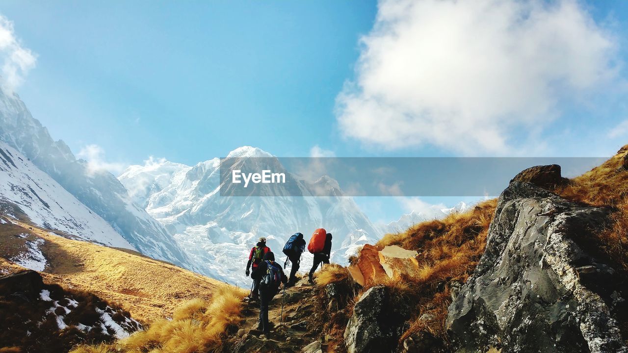 Hikers climbing on mountain against sky