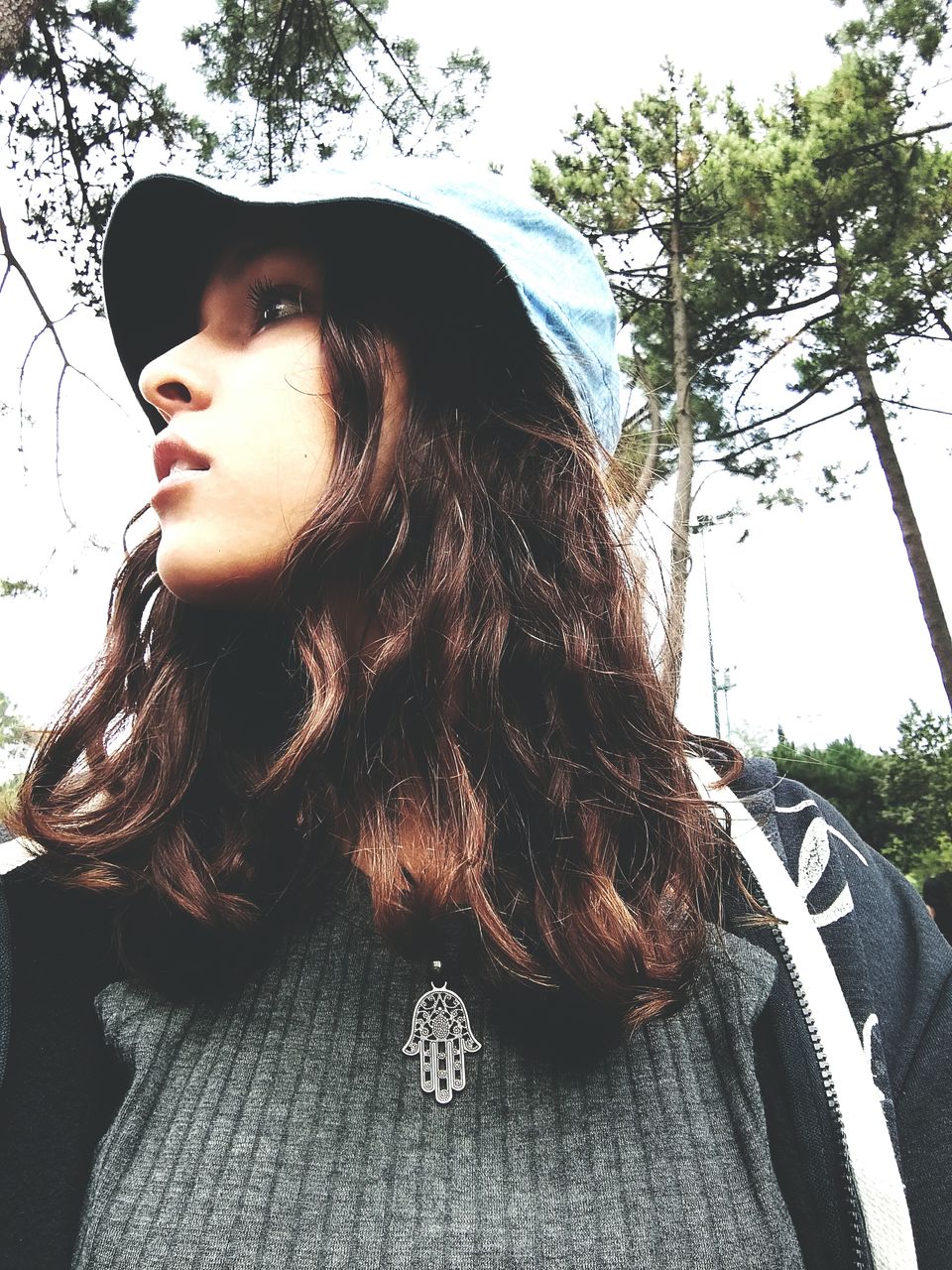 Close-up of young woman looking away against sky