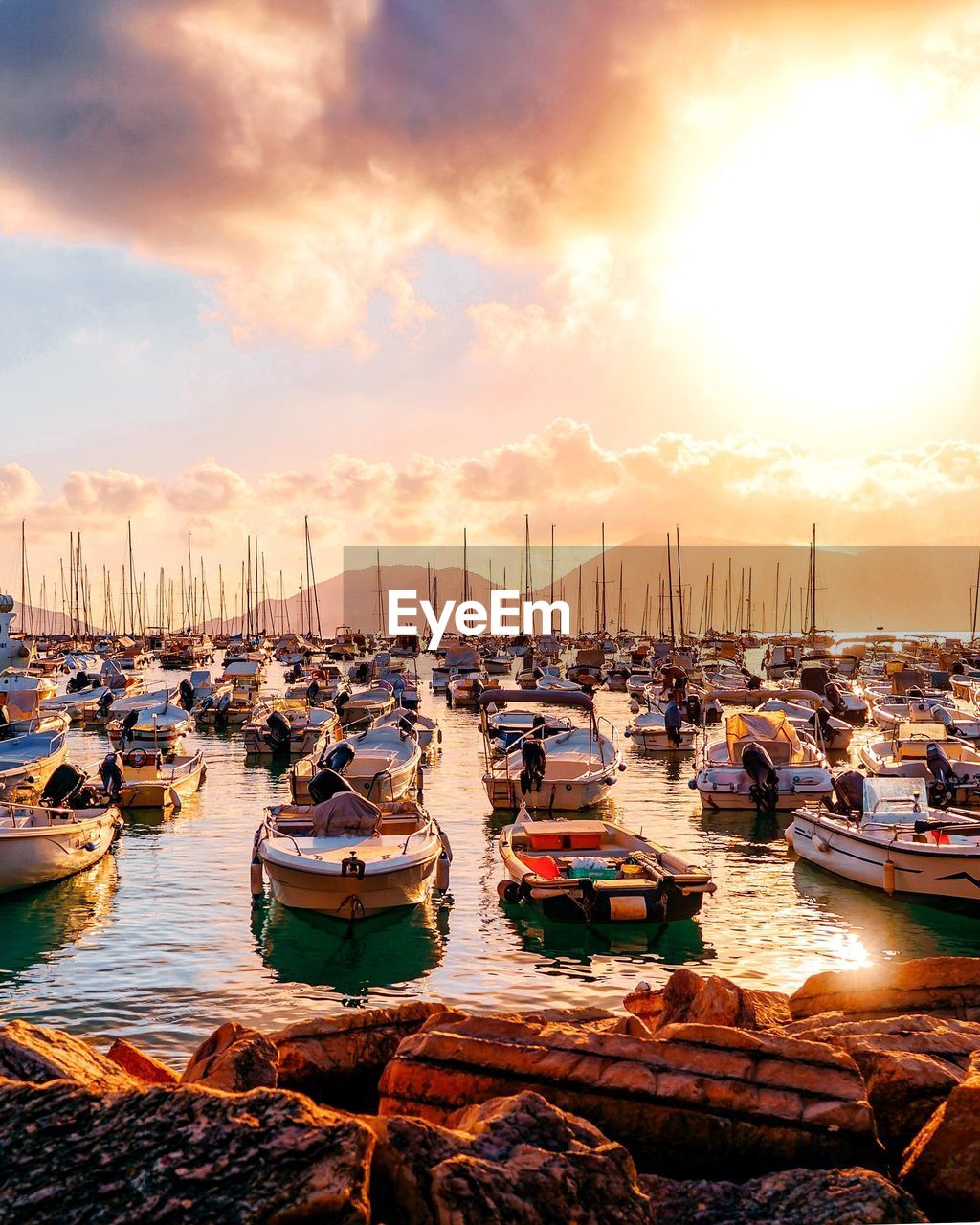 Boats moored in harbor at sunset