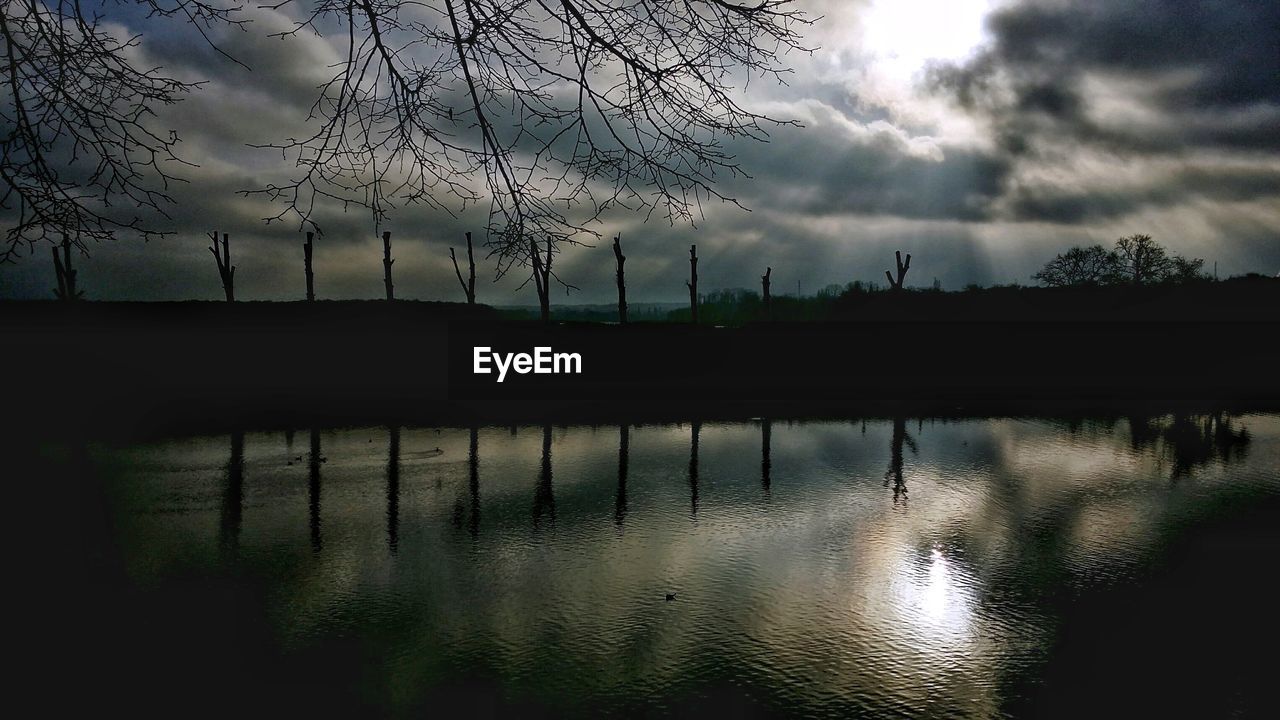 SILHOUETTE BARE TREE BY LAKE AGAINST SKY