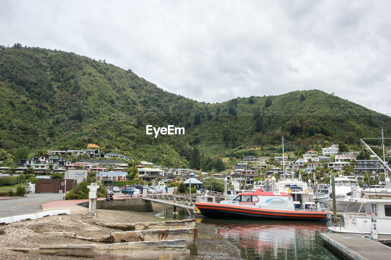 BOATS MOORED IN LAKE AGAINST MOUNTAINS