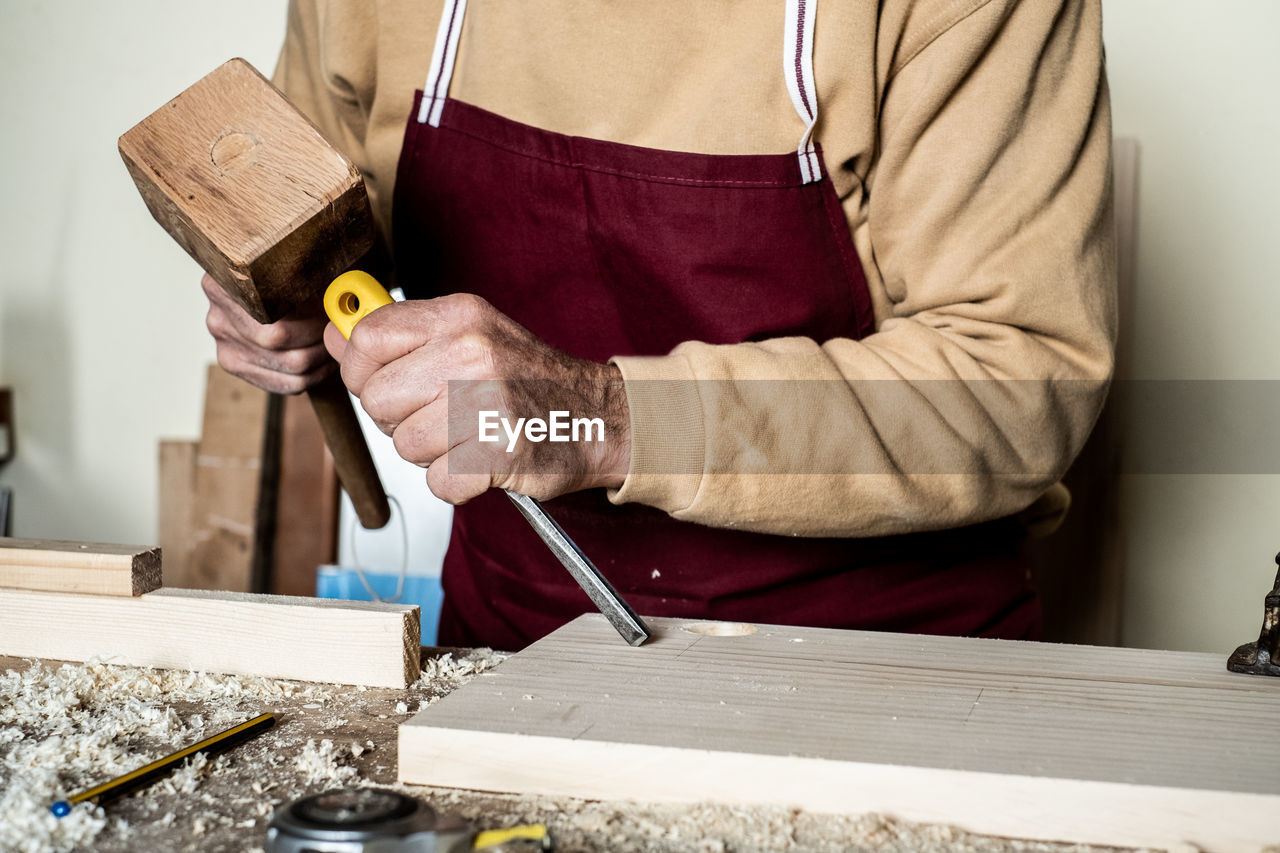 Midsection of carpenter working on wood