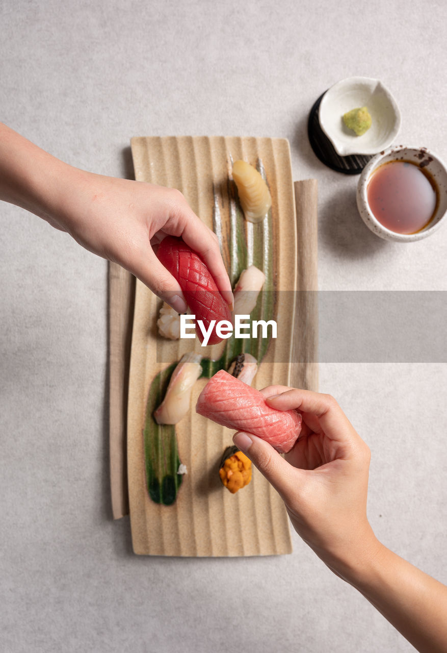 Two person holding sushi top view angle