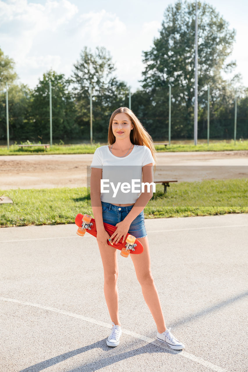 Portrait of a happy teenage girl holding a skateboard