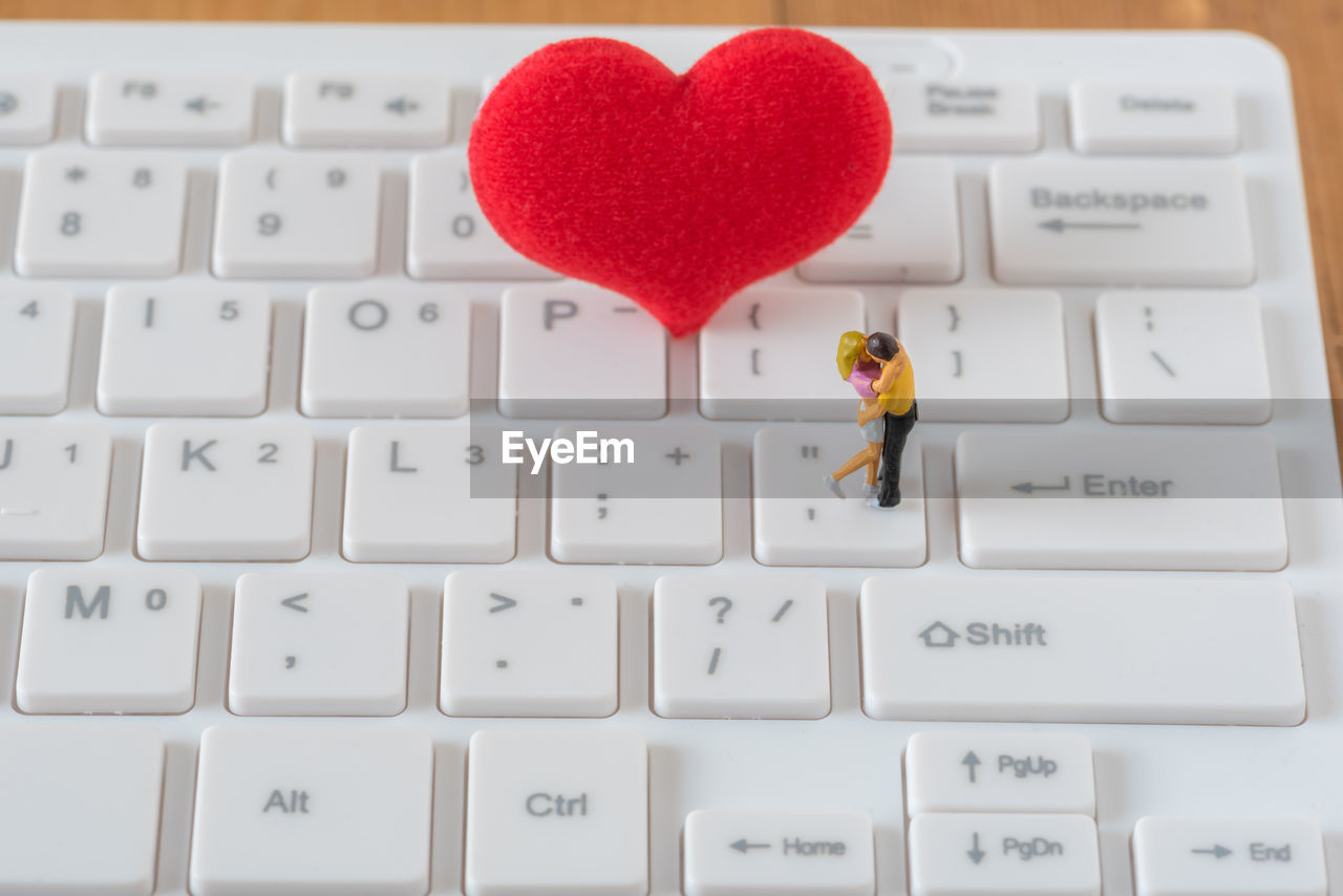 Close-up of heart shape and figurines on keyboard