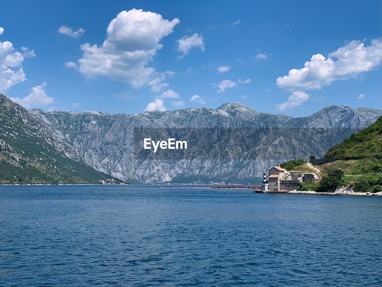 Scenic view of sea by mountains against sky