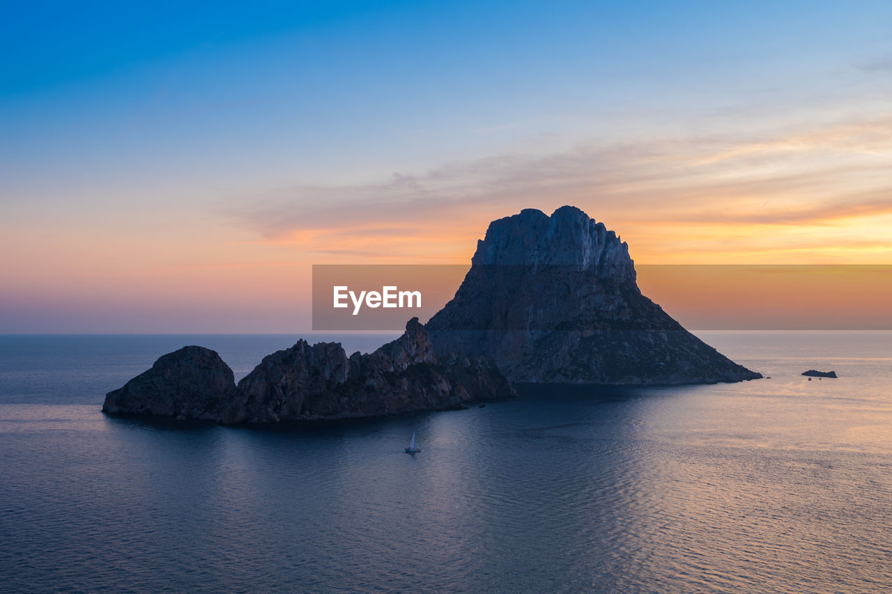 Scenic view of es vedrà island at sunset in mediterranean sea.ibiza