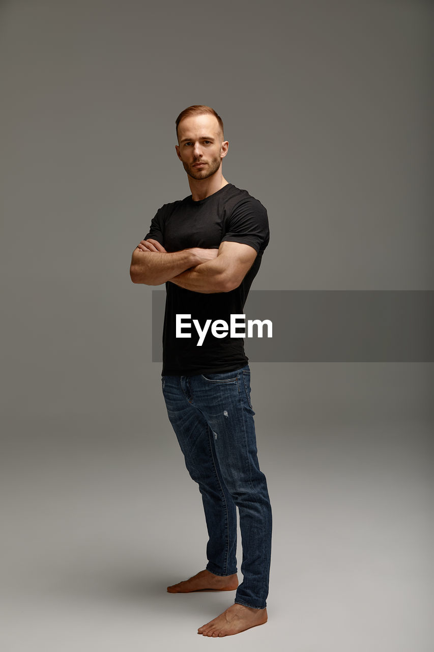 full length of young man standing against gray background