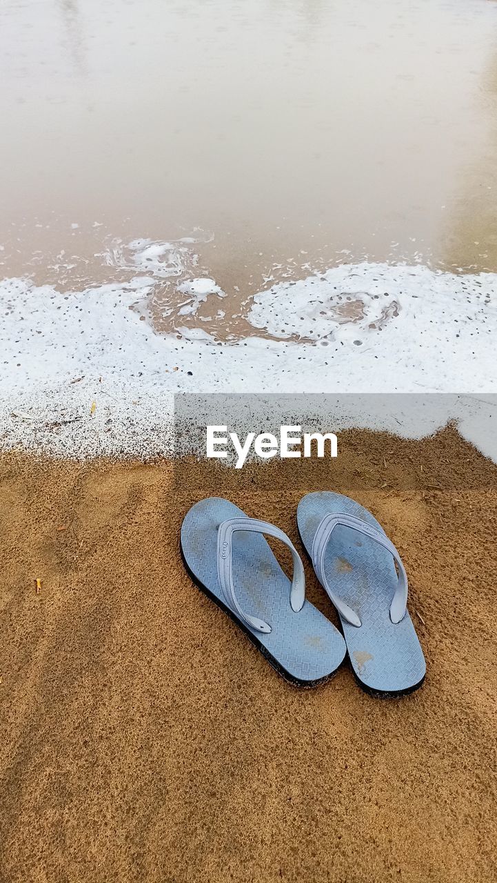 beach, land, sand, water, flip-flops, shoe, pair, nature, footwear, no people, sandal, day, tranquility, sea, high angle view, absence, reflection, wet, beauty in nature, shore, outdoors, blue, wave, body of water, natural environment, vacation