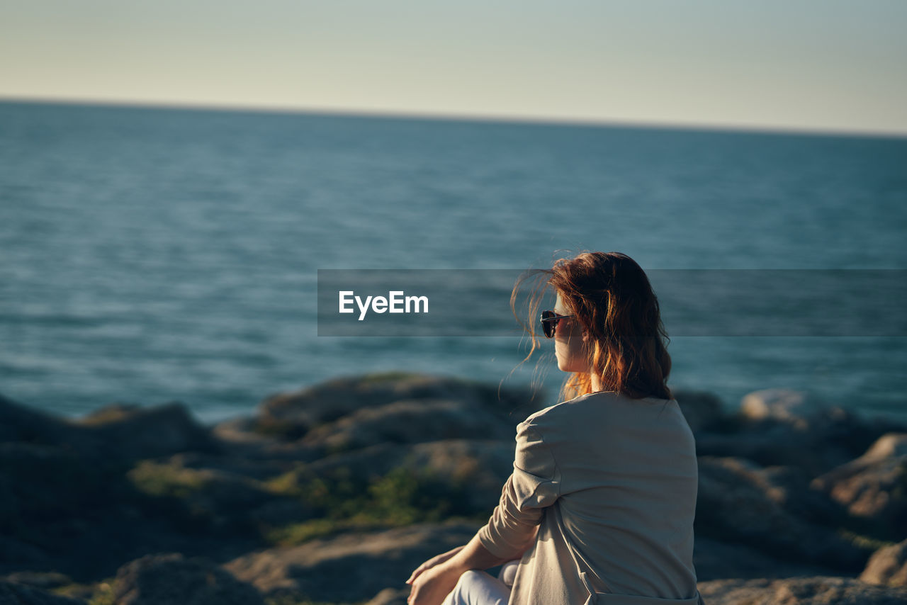 Woman looking at sea against sky