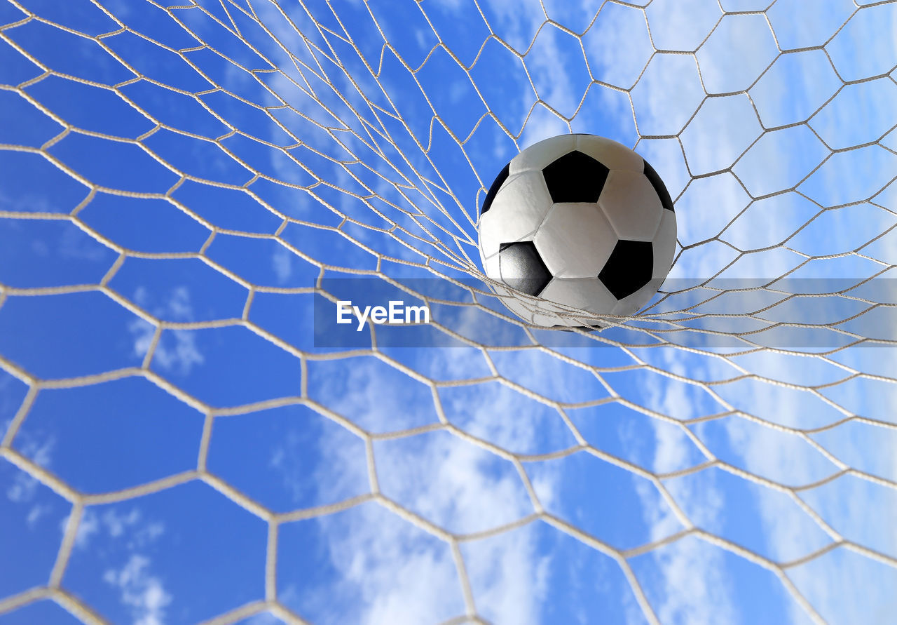 Soccer ball hitting in goal post against blue sky