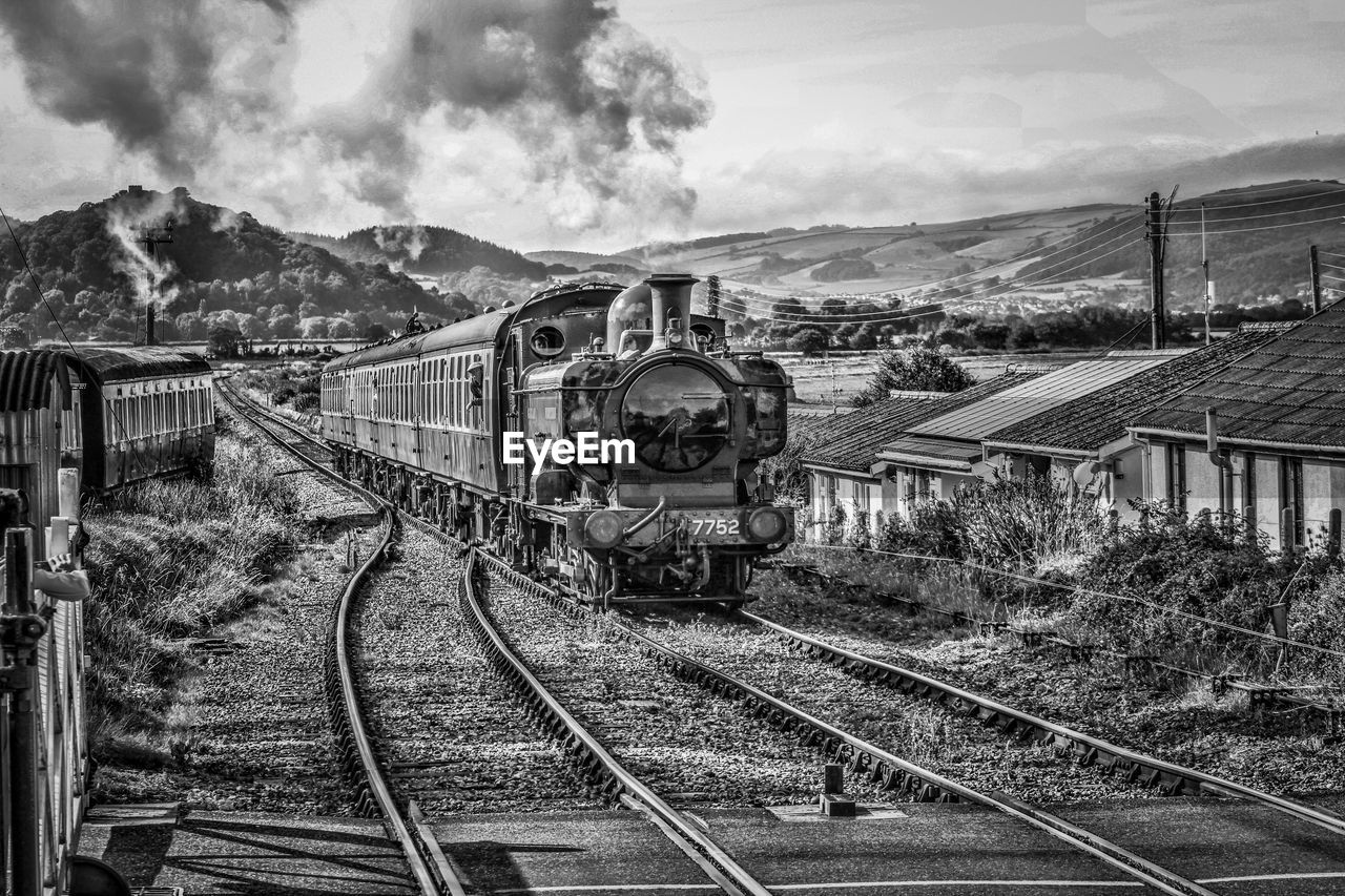 Train on railroad track against sky and rolling hills 