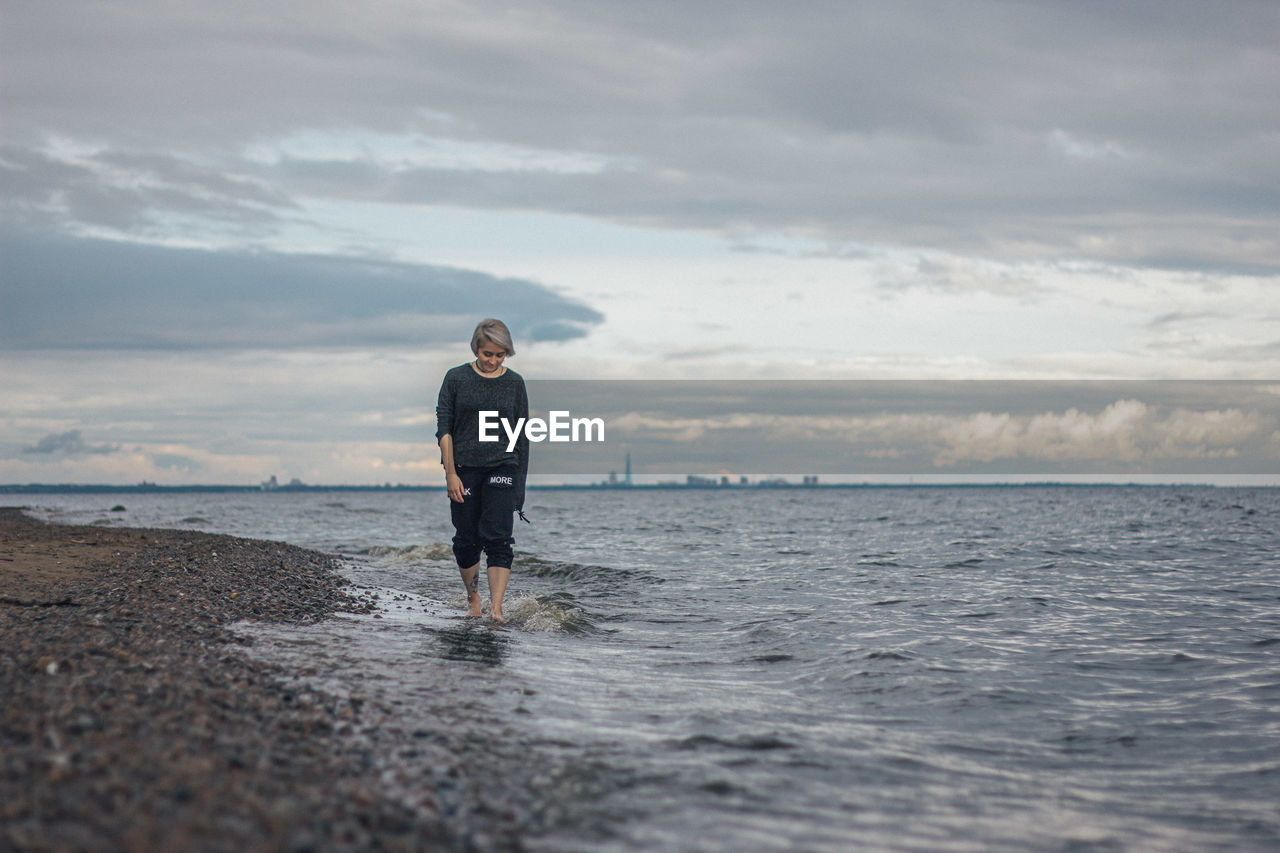 Full length of woman walking on beach against sky