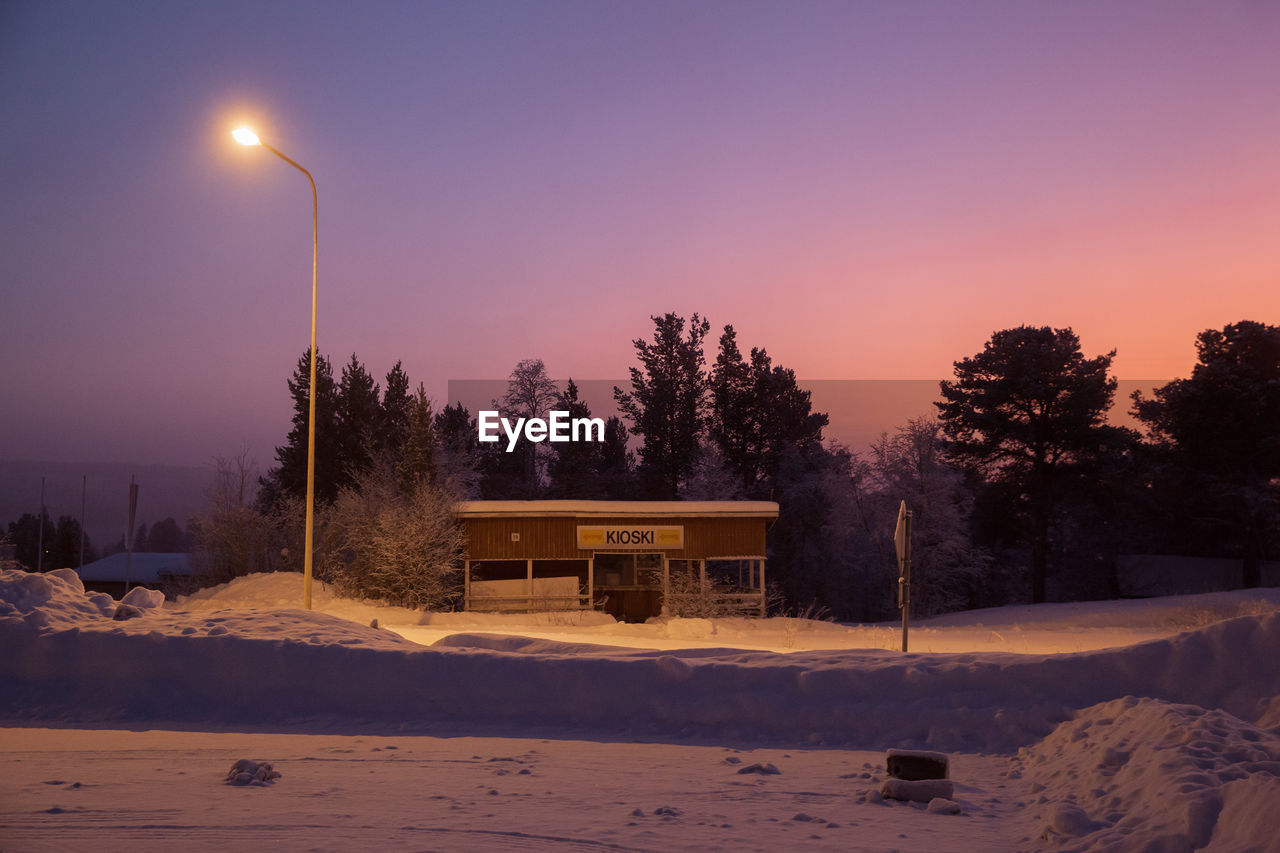 Lob cabin on snow covered field at dusk