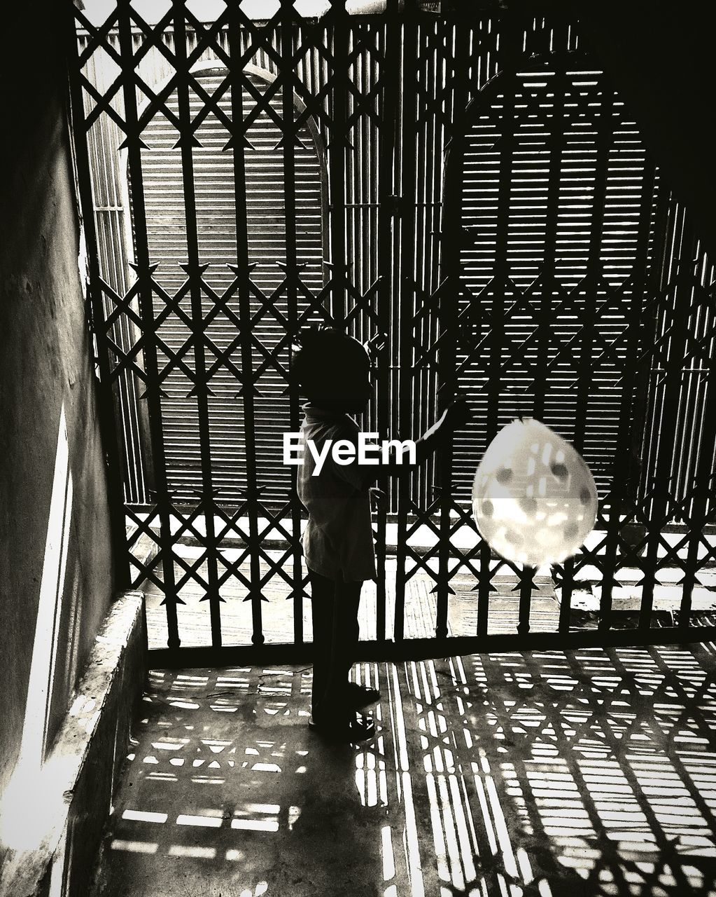 Boy playing with balloon against gate