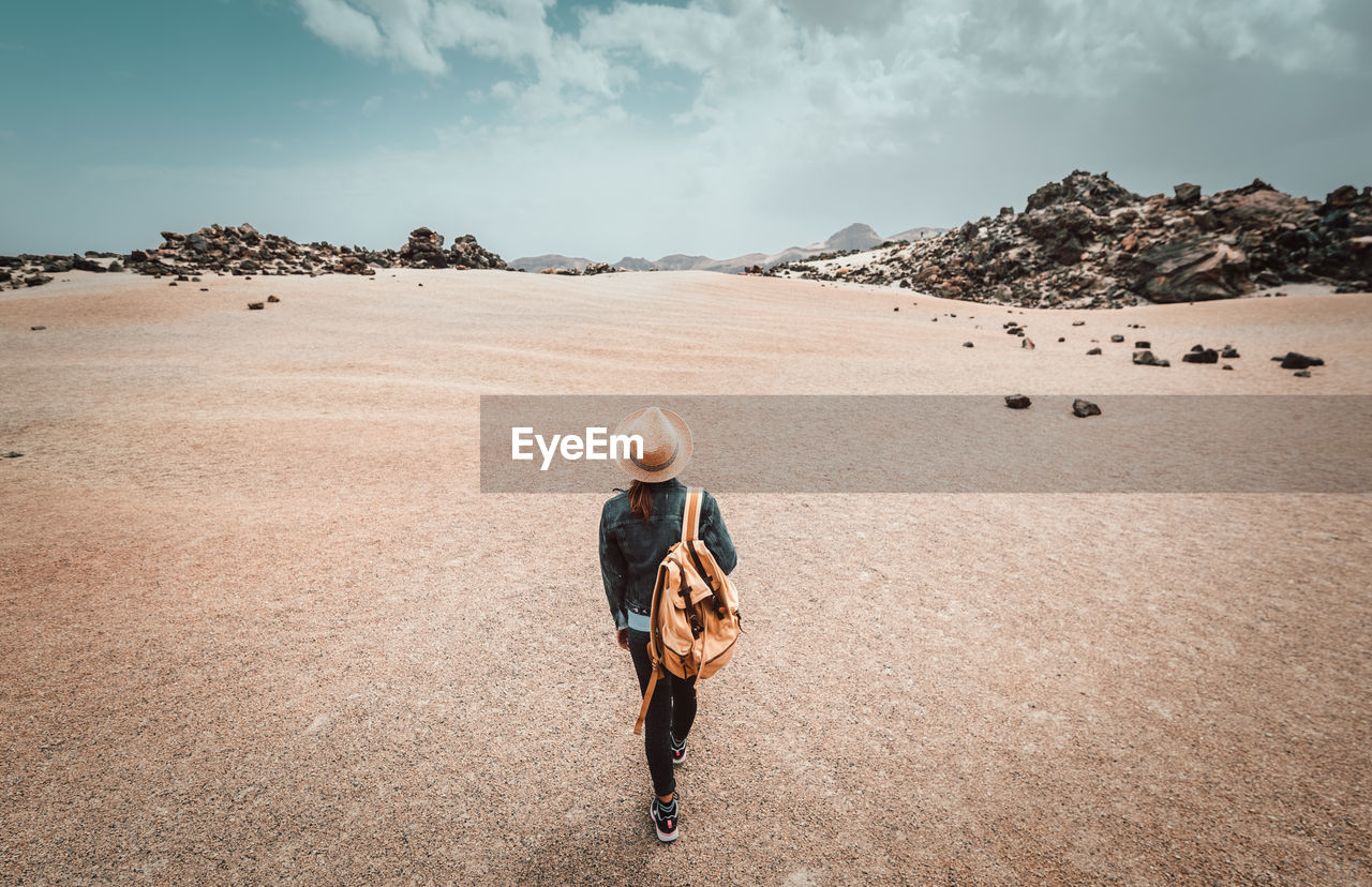 Rear view of woman with backpack walking on land