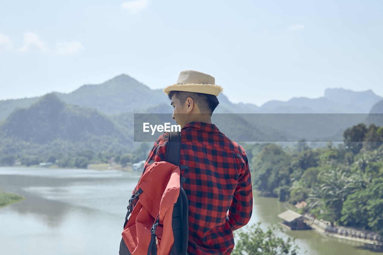 The young asian man looks out over the mountains and rivers