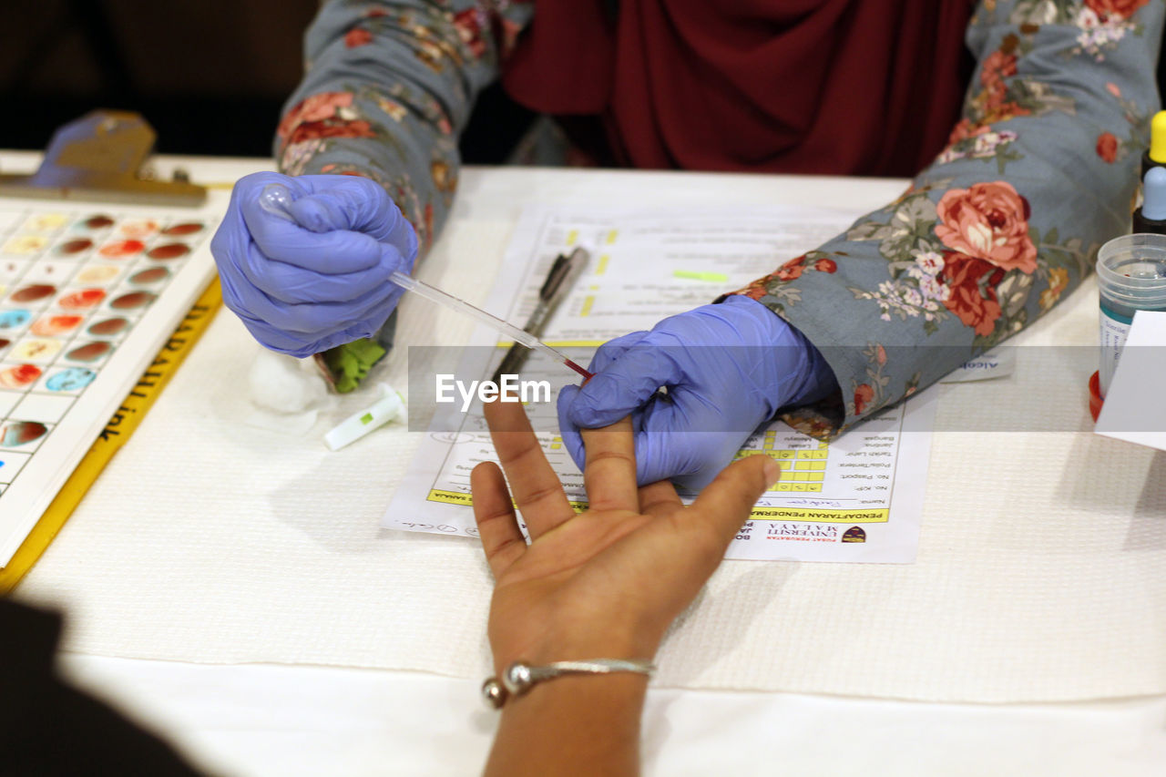 Cropped hands of doctor removing blood sample from patient finger