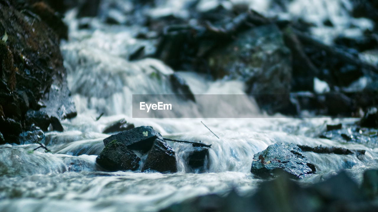 CLOSE-UP OF WATER FLOWING OVER ROCKS