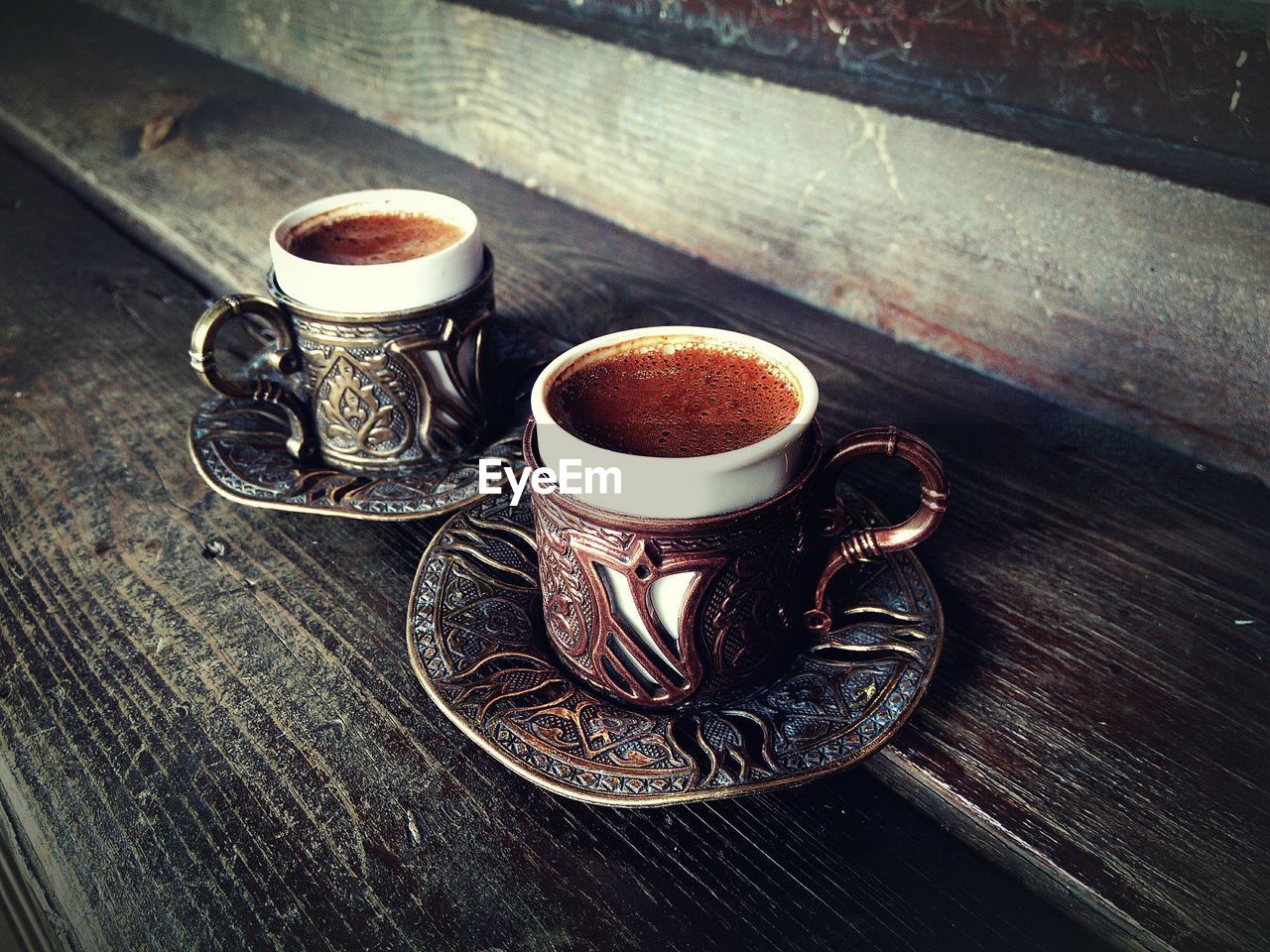 Tea in cups on plates over wooden table