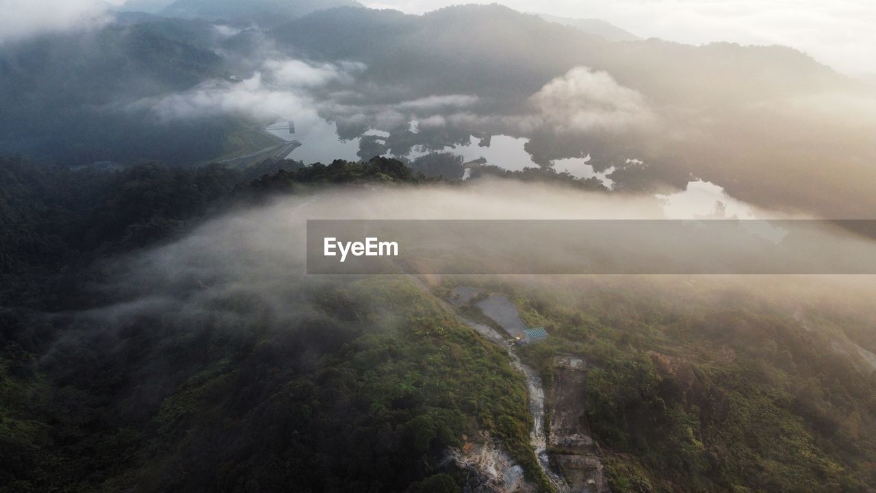 environment, fog, landscape, mountain, scenics - nature, land, nature, mountain range, cloud, beauty in nature, travel, sky, mist, forest, tree, plant, no people, outdoors, morning, travel destinations, tourism, ridge, tranquility, social issues, valley, high angle view, sun, mountain peak, sunlight, high up, hill station, day, summer, environmental conservation, aerial view, trip, vacation, rural scene, architecture, sunbeam, plateau, non-urban scene, atmospheric mood, holiday, journey