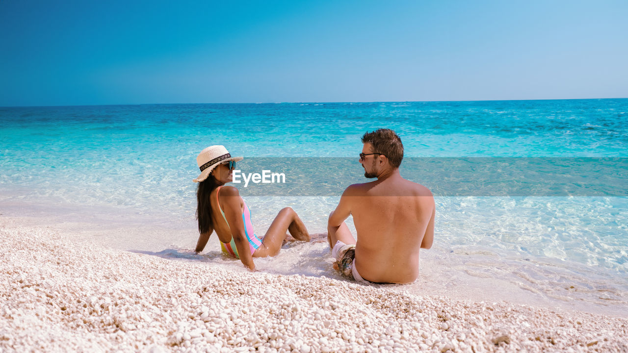 rear view of woman sitting on beach