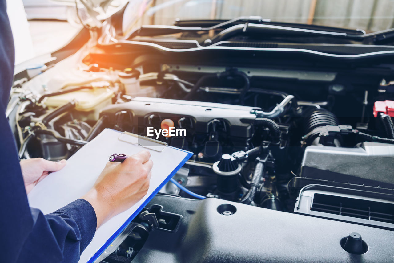 Cropped hands of mechanic repairing car in garage