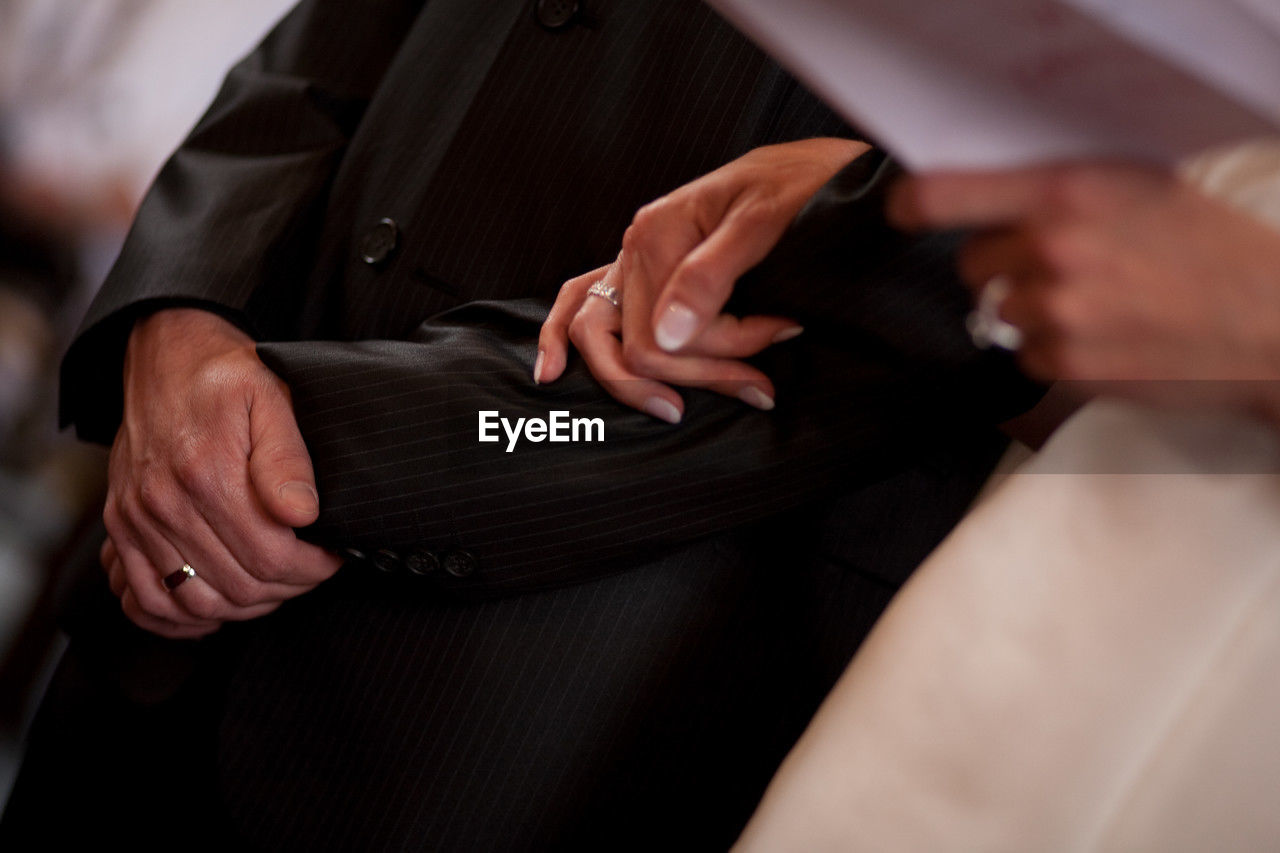 adult, hand, men, formal wear, two people, women, clothing, midsection, indoors, ceremony, bride, tuxedo, wedding dress, person, business, ring, love, married, female, wedding, emotion, close-up, dress, event, togetherness, selective focus, holding hands, positive emotion