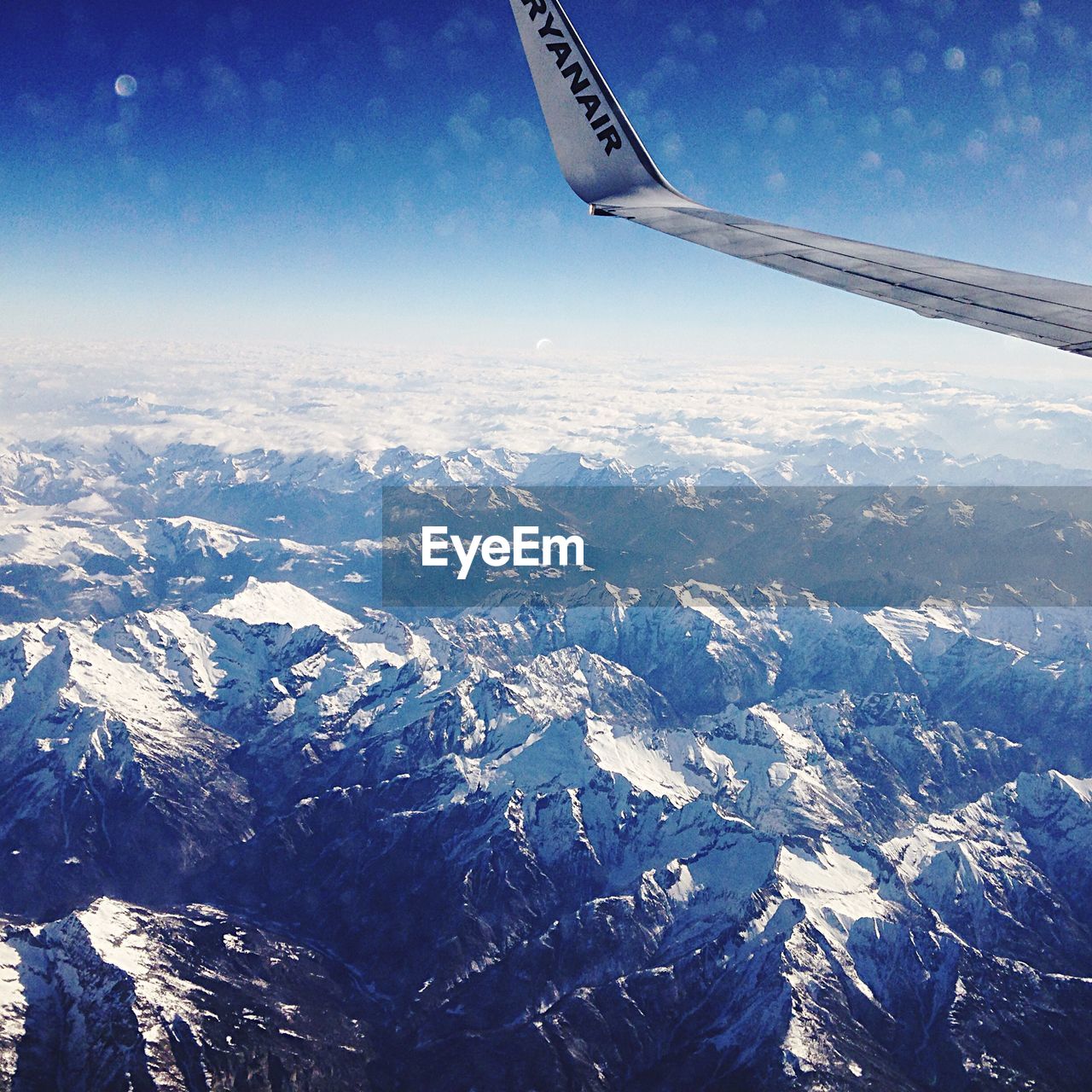 Cropped image of airplane over snowcapped mountains