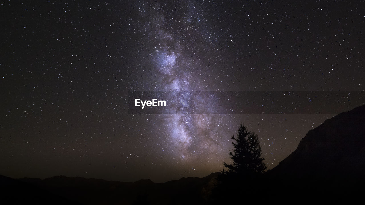 Low angle view of silhouette mountain against star field