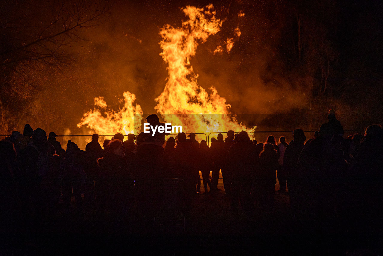 Silhouette people against fire at night