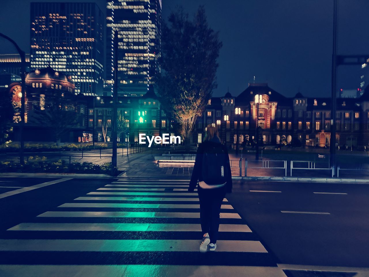 Rear view of woman walking on road at night