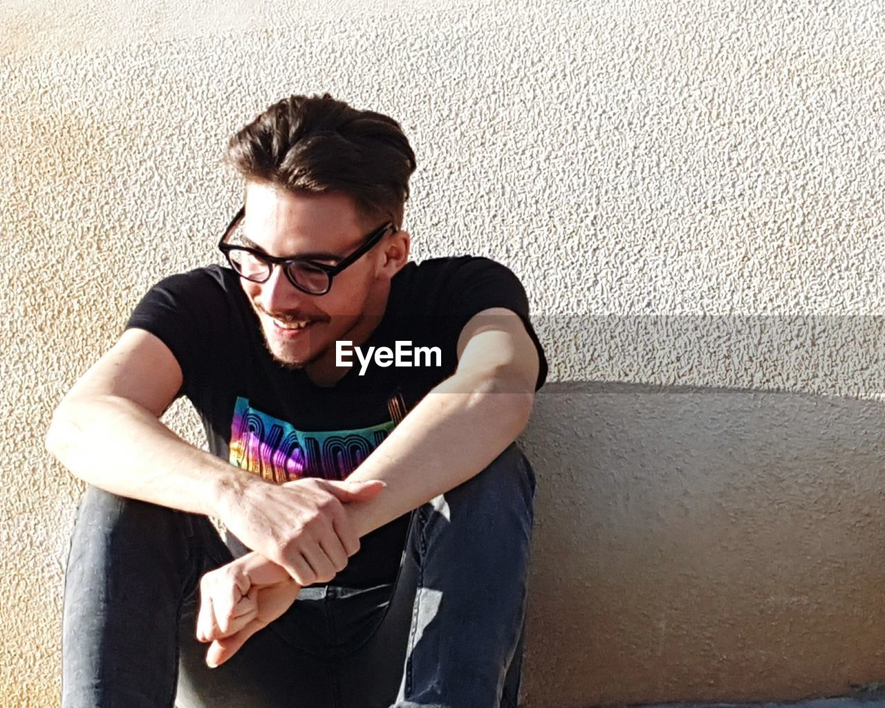 Happy man sitting against wall