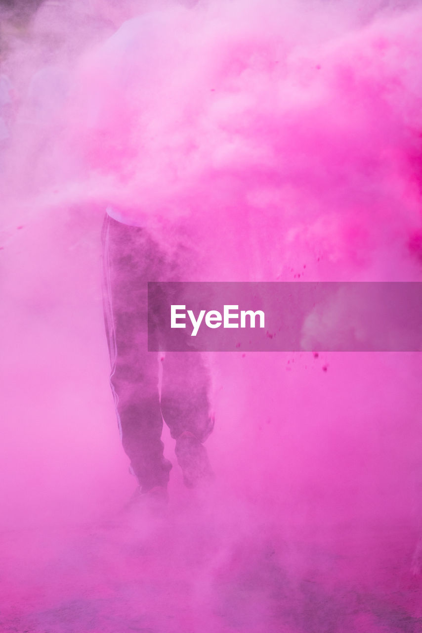 Low section of person standing in pink powder paint