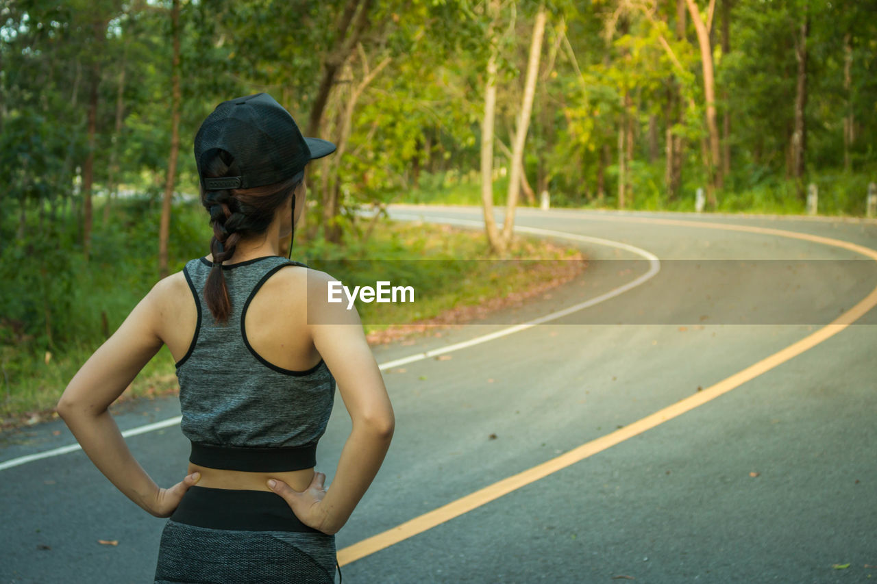 Rear view of athlete exercising on road amidst trees