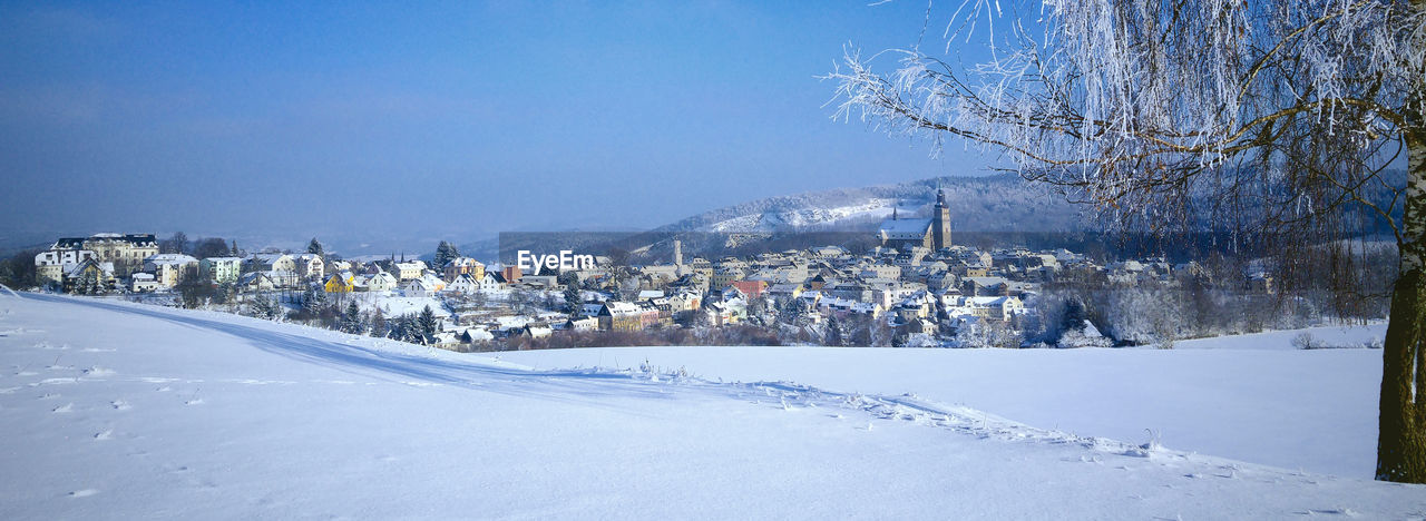 Snow covered landscape against blue sky