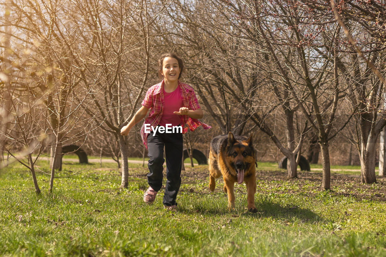 portrait of young woman playing with dog on grassy field