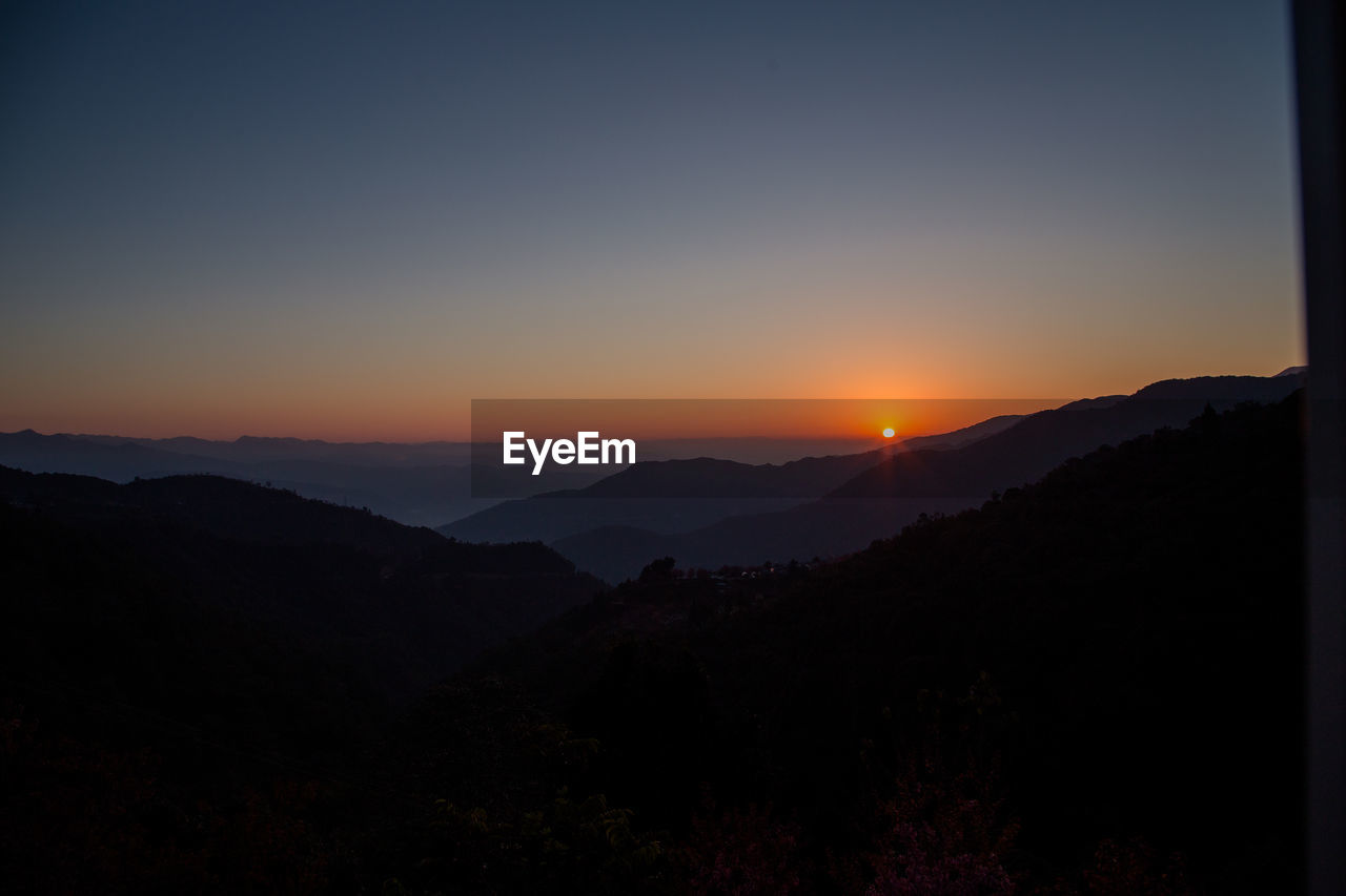 SCENIC VIEW OF SILHOUETTE MOUNTAINS AGAINST ORANGE SKY