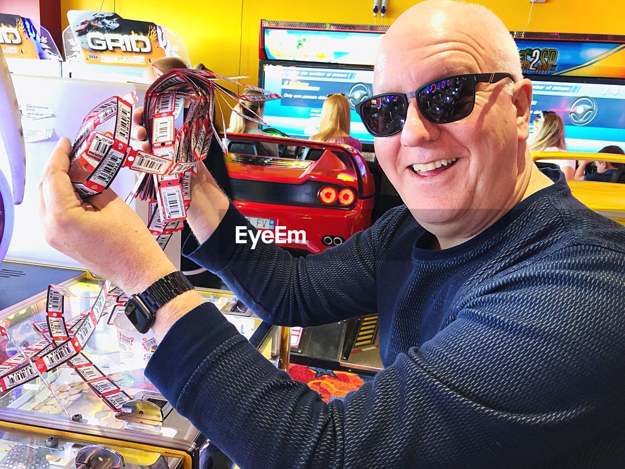 PORTRAIT OF SMILING MAN HOLDING SUNGLASSES WHILE STANDING ON DISPLAY