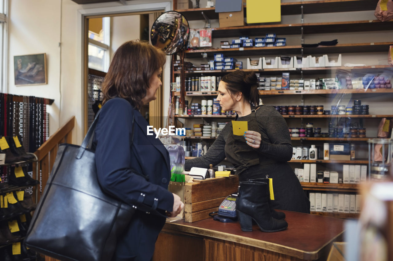 Female holding name tag while standing with customer at shoe store