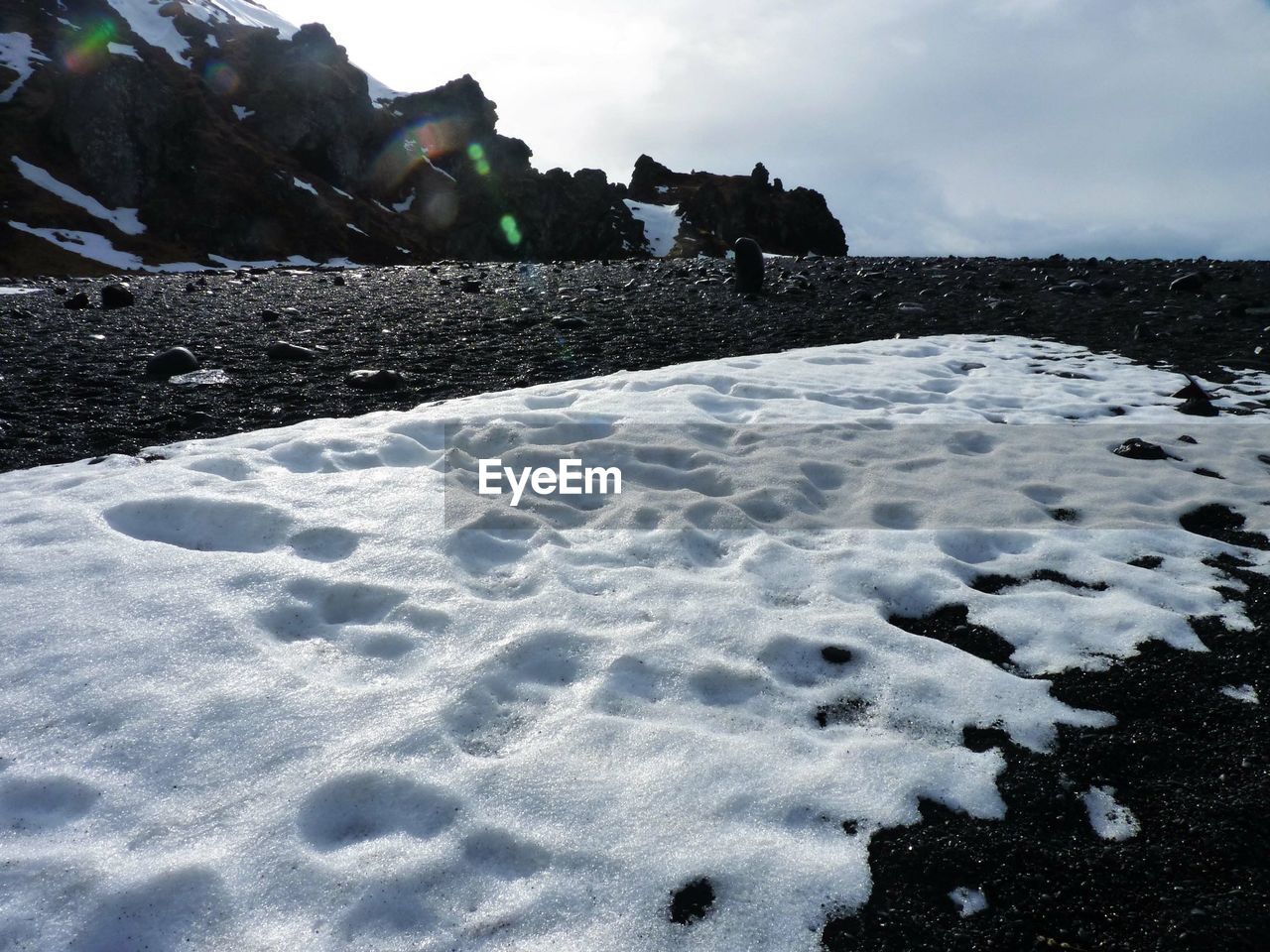 Snow covered land by mountain against sky