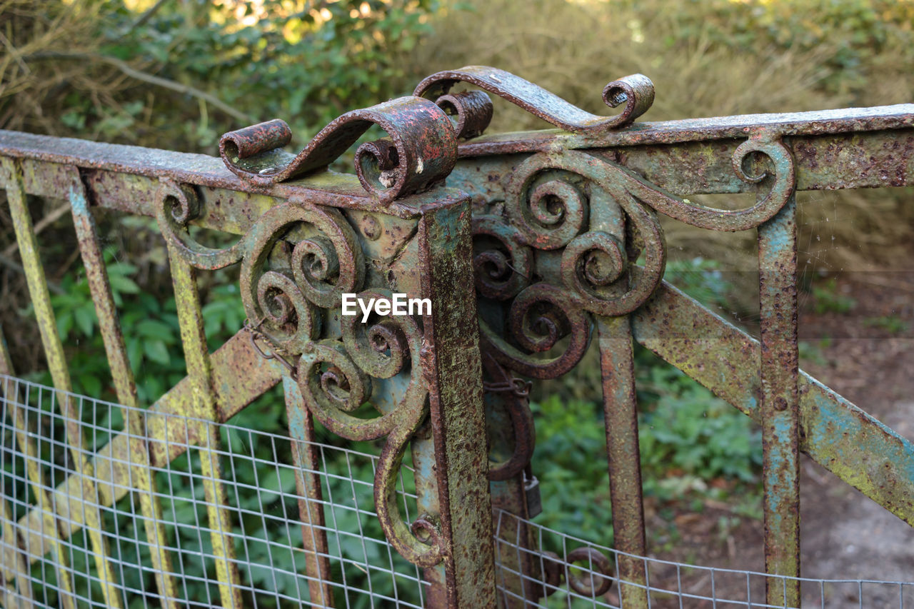 CLOSE-UP OF RUSTY METAL CHAIN ON FENCE