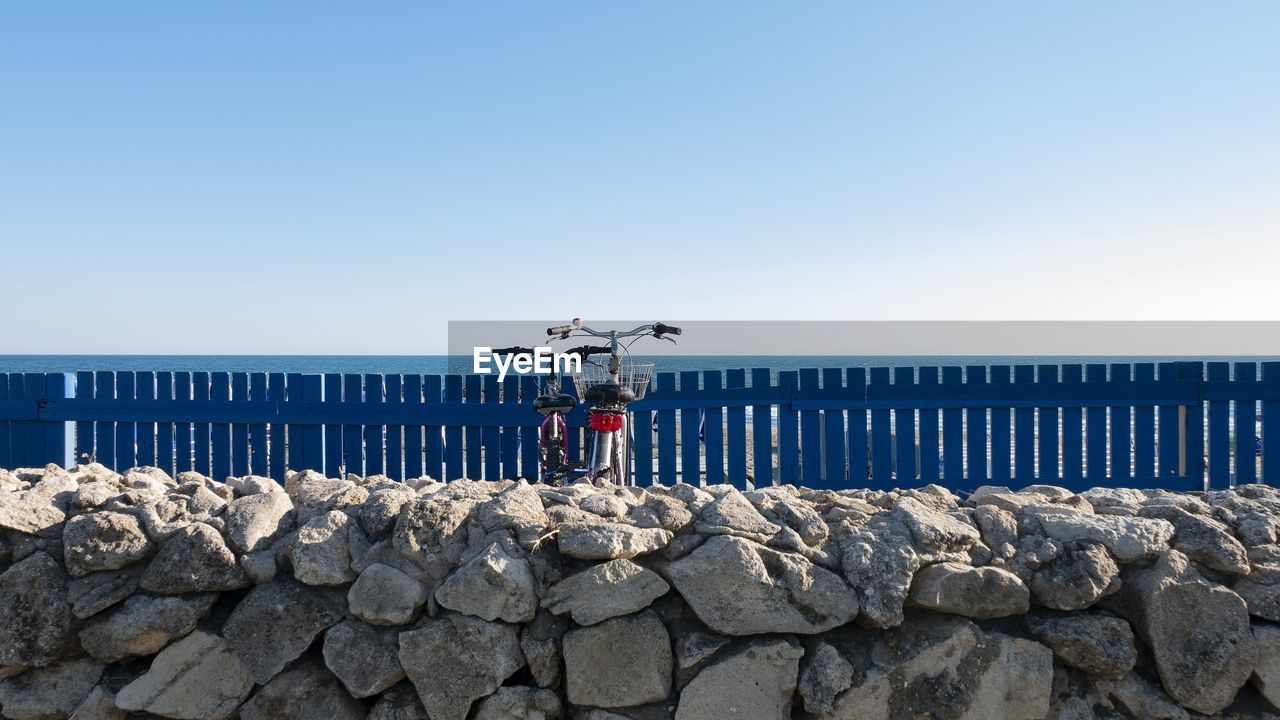 Deck chairs on rocks against clear blue sky