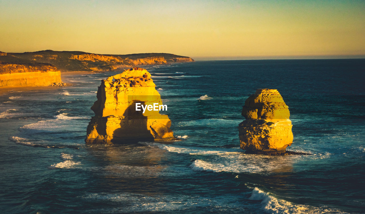 Scenic view of rock formation in sea against sky during sunset