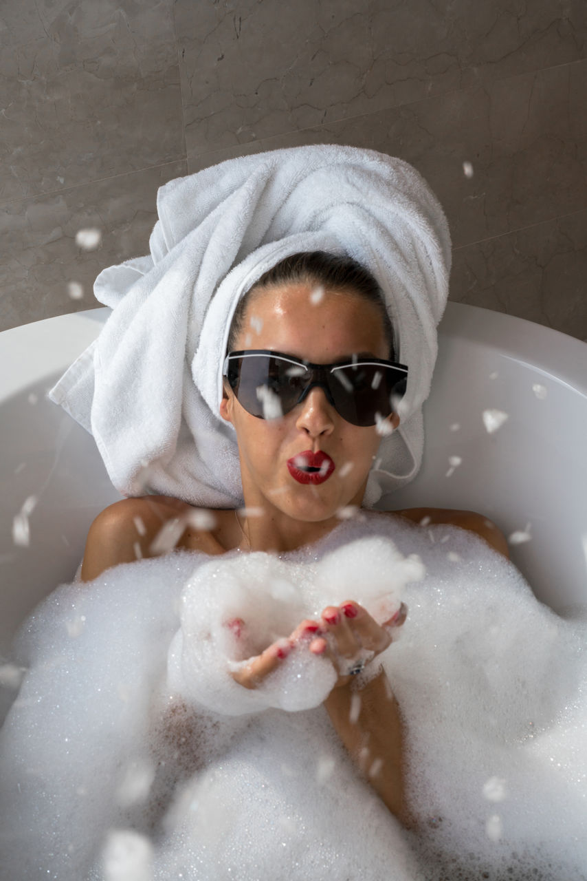 Woman blowing foam in the bathtub