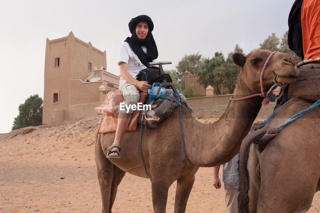 Portrait of young man on camel at desert