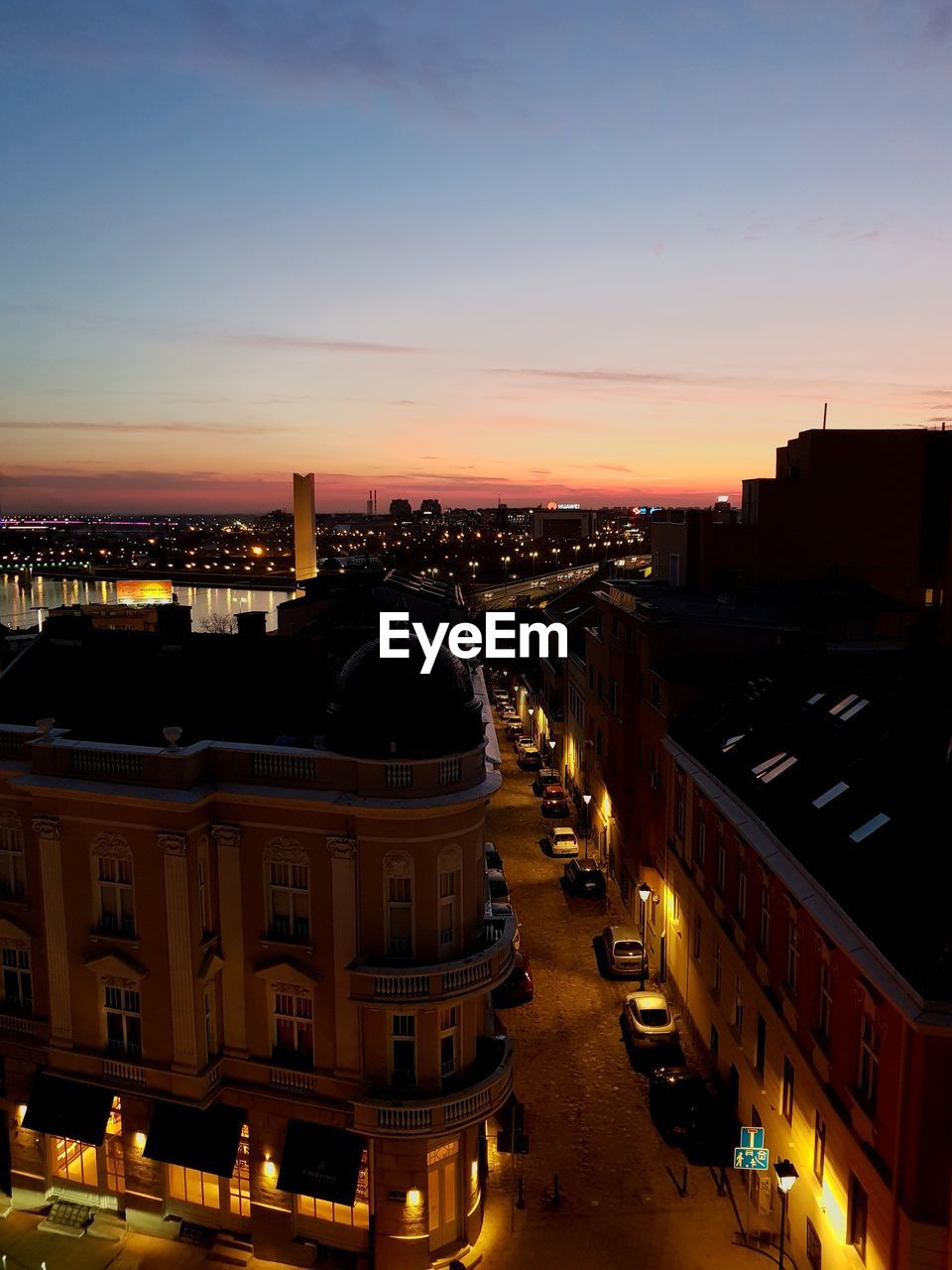 HIGH ANGLE VIEW OF ILLUMINATED BUILDINGS IN CITY DURING SUNSET