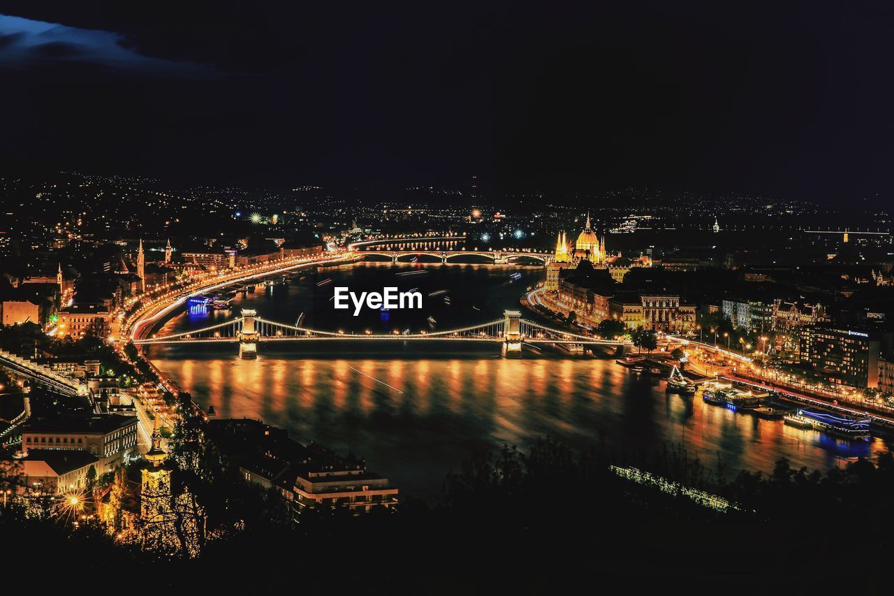 Aerial view of illuminated bridges over river against sky at night