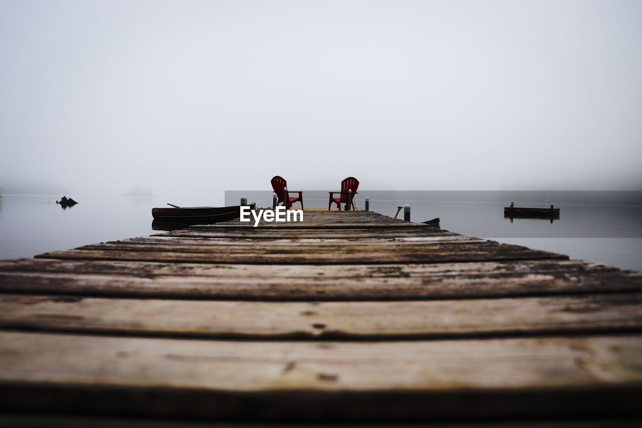 Surface level of pier over lake against sky during foggy weather