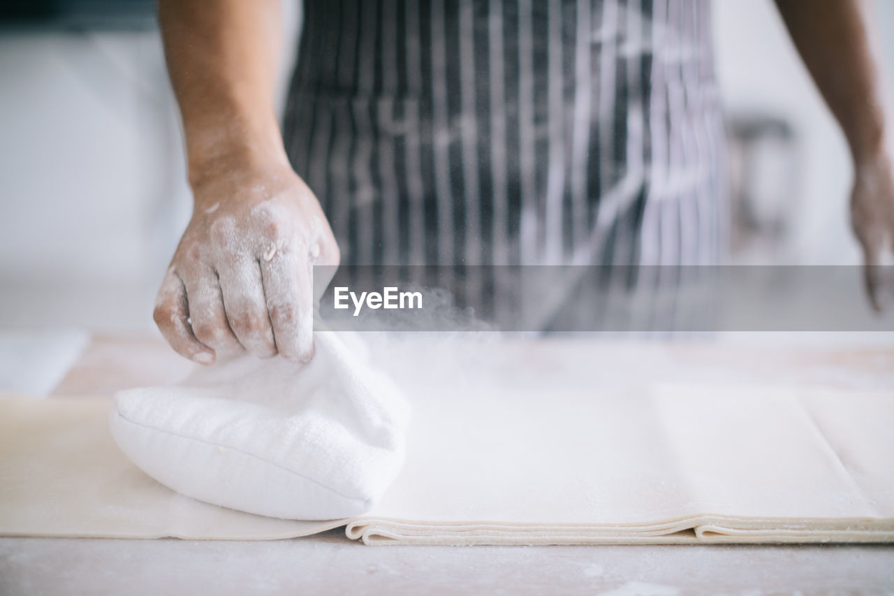 Midsection of chef using flour to make noodles